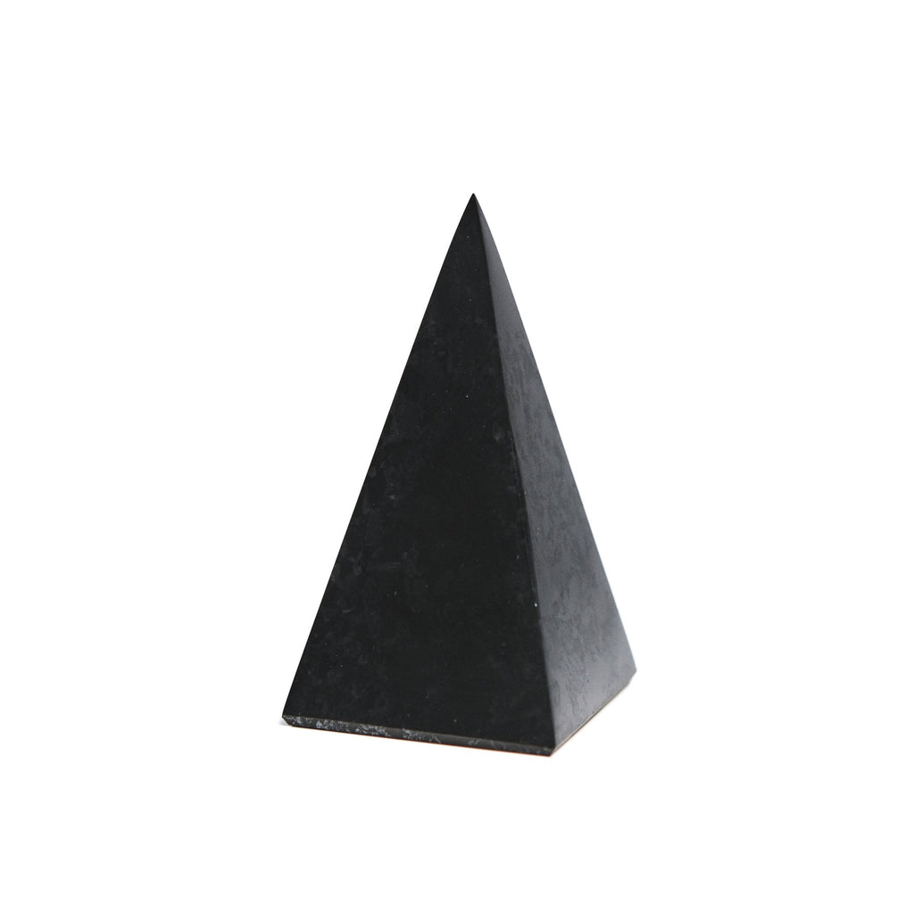 Angled close-up of a tall polished shungite pyramid with a square base and dark triangular faces.
