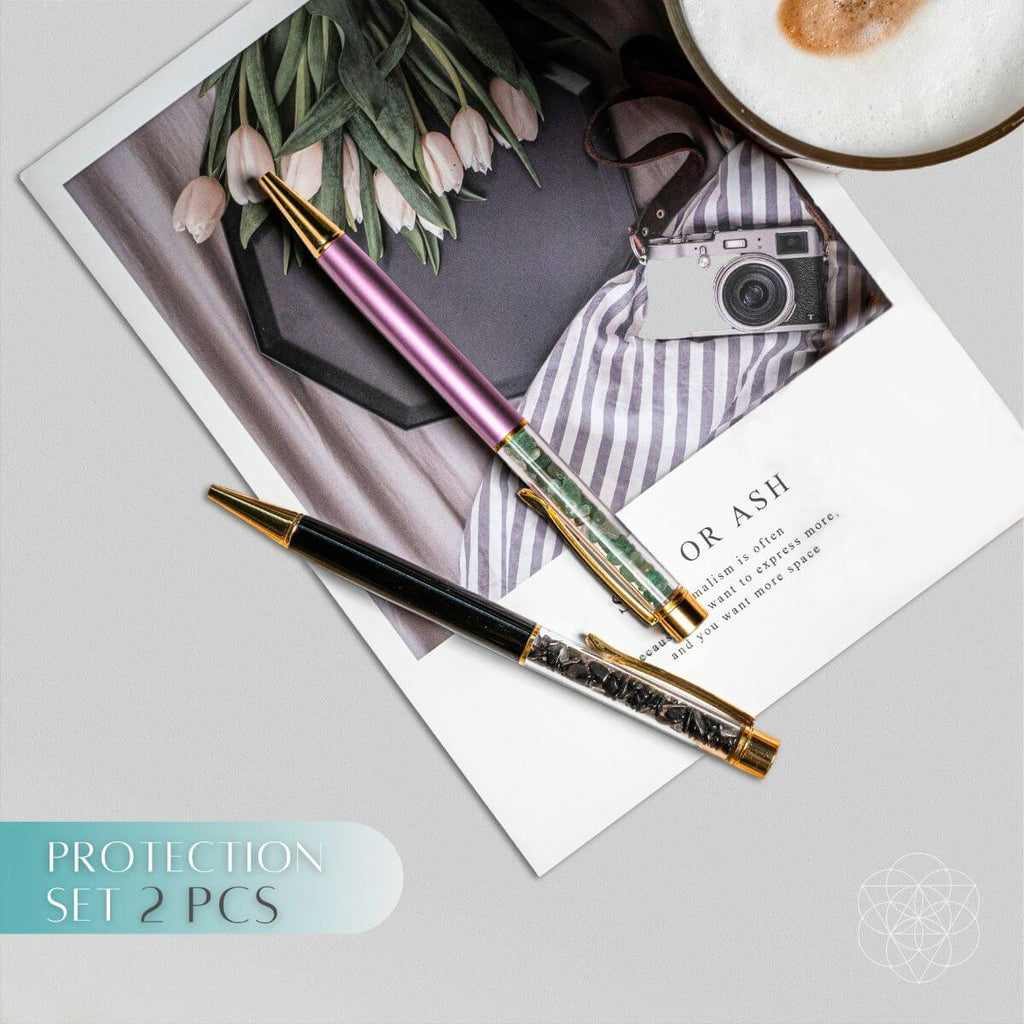 Black obsidian and lavender green aventurine crystal pens with gold-tone accents on a magazine.
I