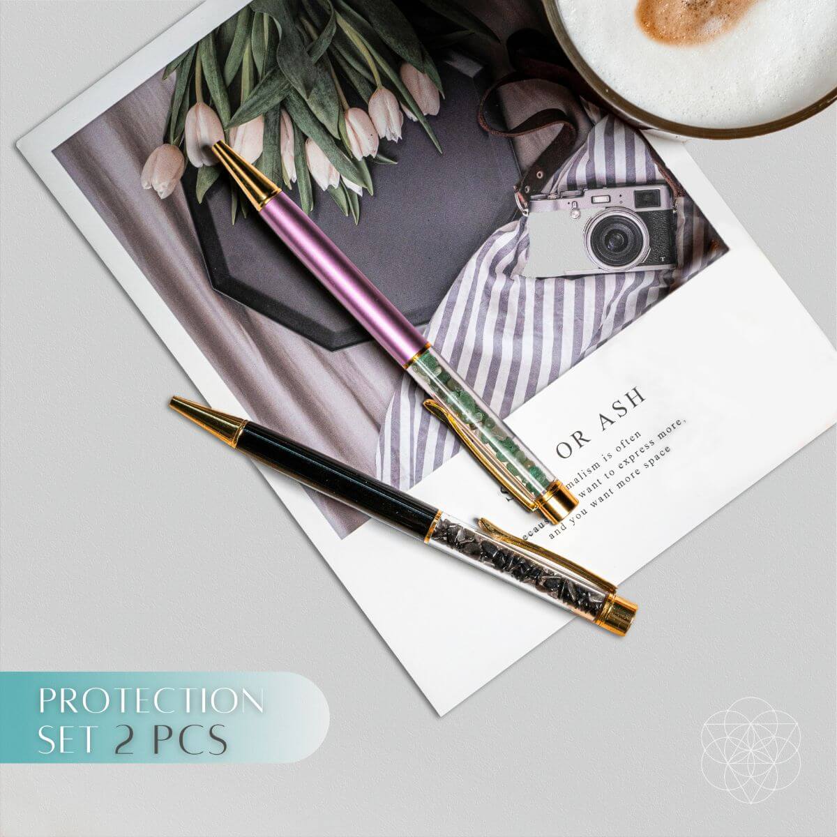 Black obsidian and lavender green aventurine crystal pens with gold-tone accents on a magazine.
I