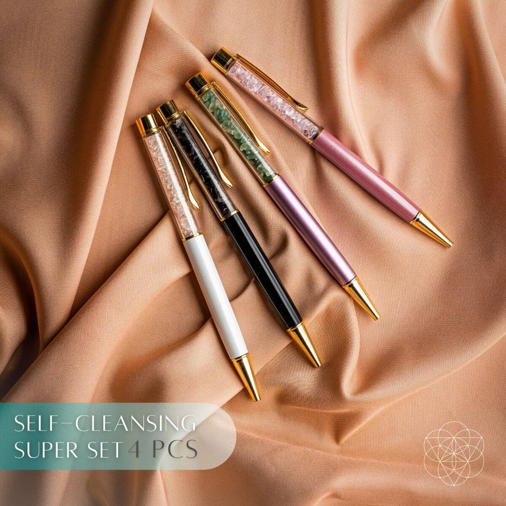 Four crystal-chip pens in white, black, lavender, and pink with gold-tone accents on peach fabric.