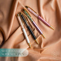 Four crystal-chip pens in white, black, lavender, and pink with gold-tone accents on peach fabric.