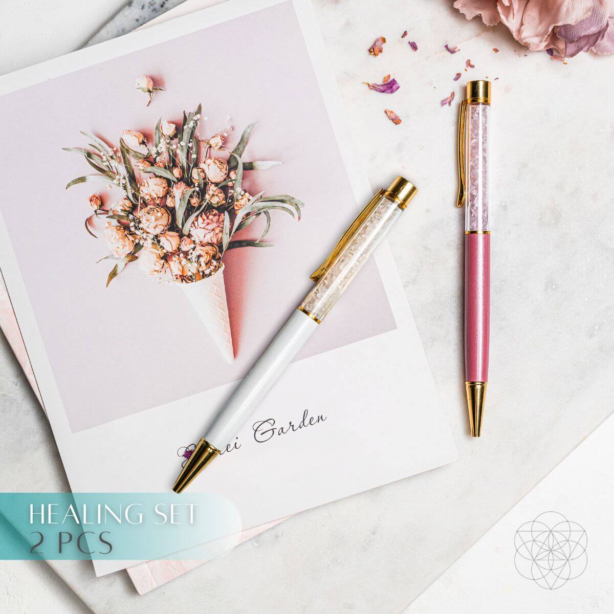 White clear quartz and pink rose quartz pens with gold-tone accents beside a floral print.