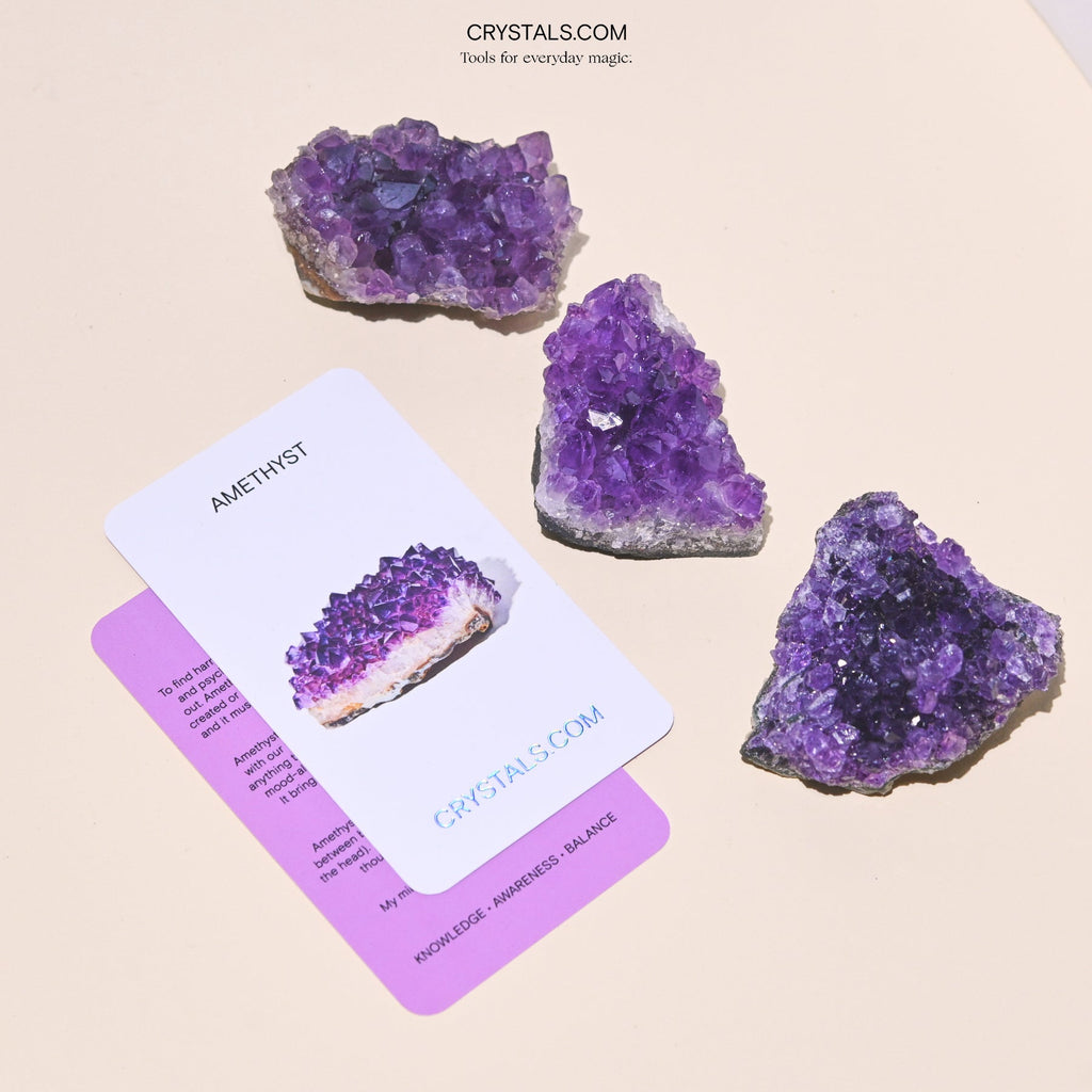 Three violet amethyst clusters in rectangular and triangular shapes beside collector cards.
